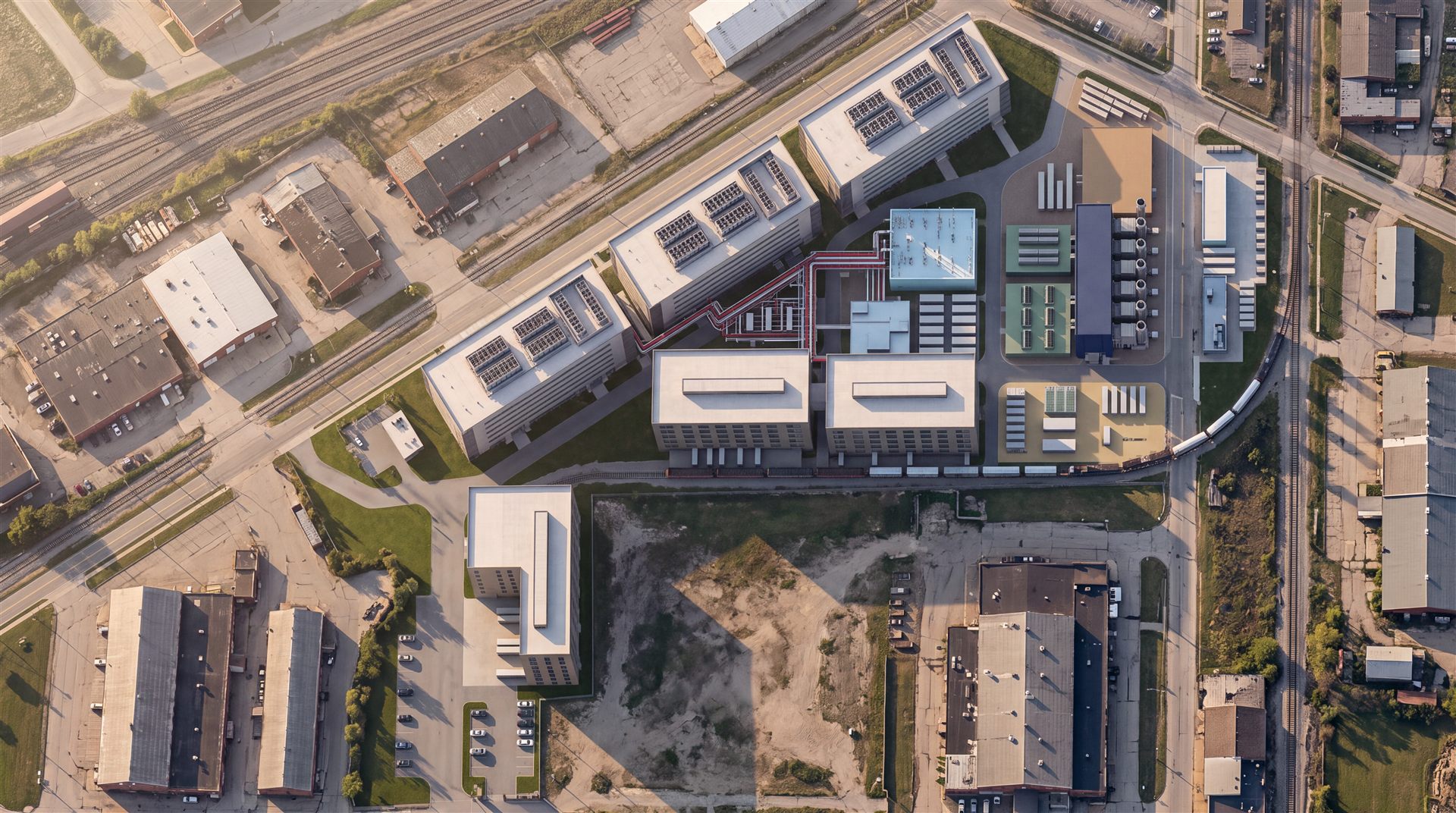 Golden-hour aerial of the campus: three data halls along Kirby Ave, manufacturing buildings, power plant with heat recovery units and stacks, hydrogen plant and rail spur